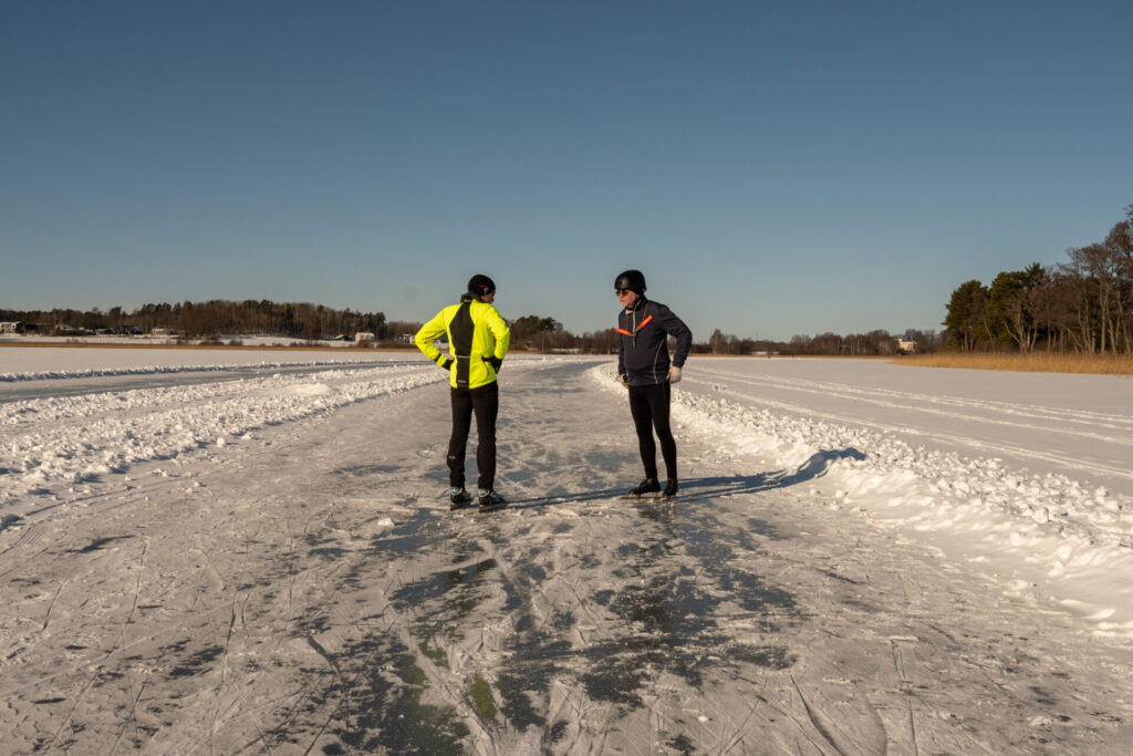 Två män står och paratar på isen.
