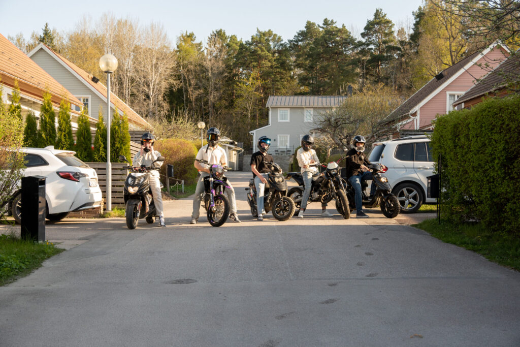 Fem mopeder med förare uppställda i en rad för fotografering.