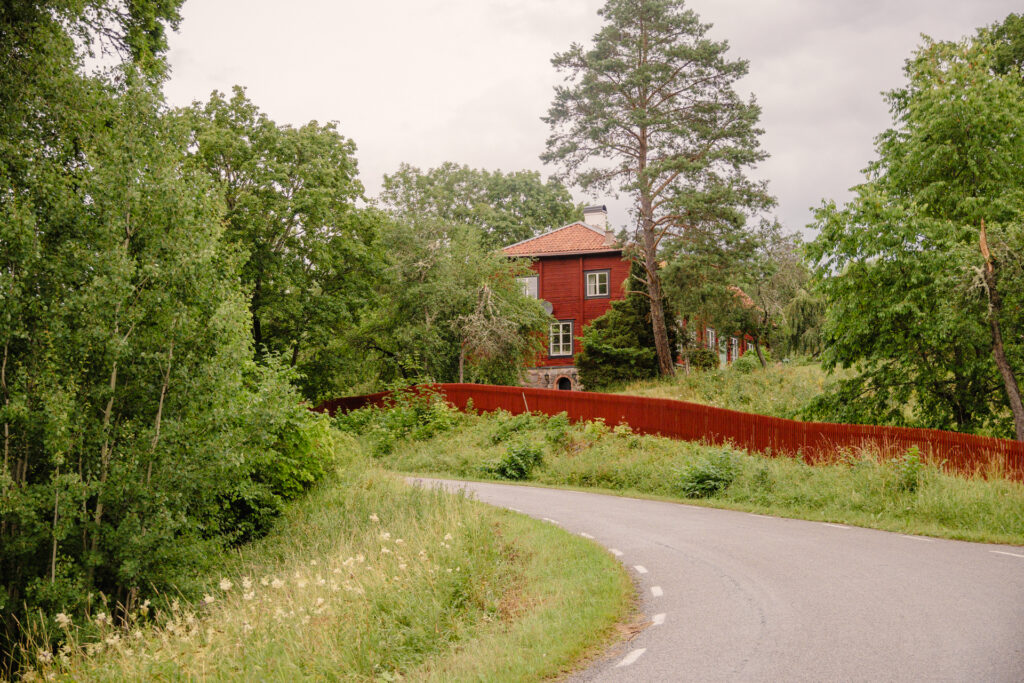 En röd herrgårdsliknande byggnad vid Ytterkvarn, omgiven av grönska och en grusväg.