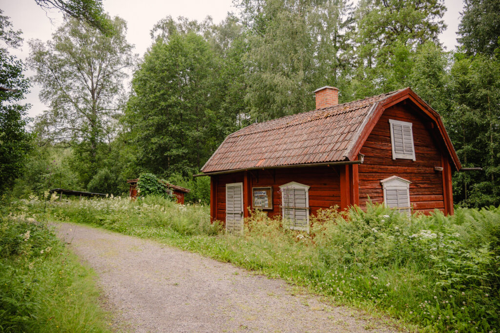 Den historiska mjölnarstugan vid Ingbo kvarn, omgiven av frodig vegetation.