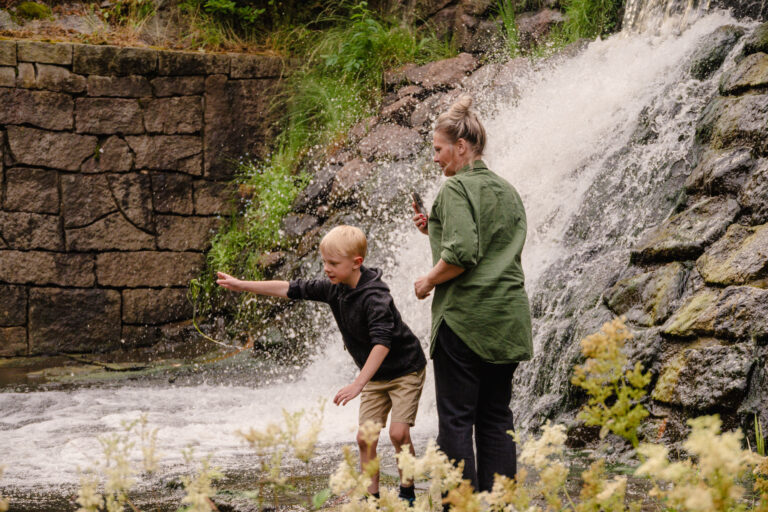 Jenny och ett barn leker vid vattenfallet vid Ytterkvarn.