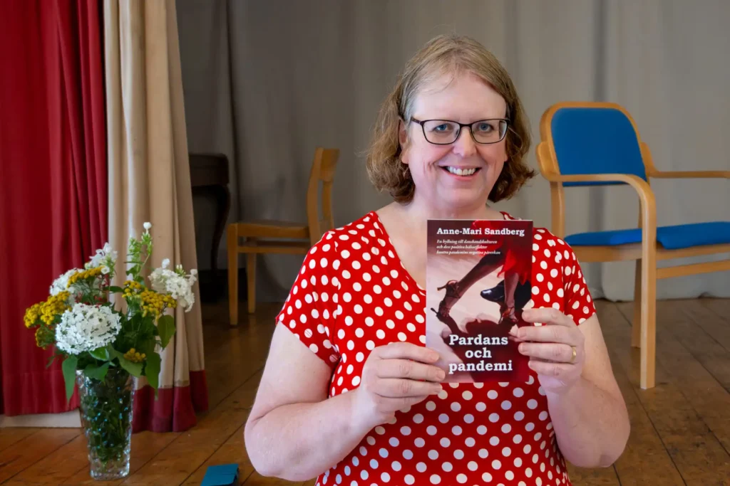 Mia Sandberg håller upp sin bok "Pardans och Pandemi".